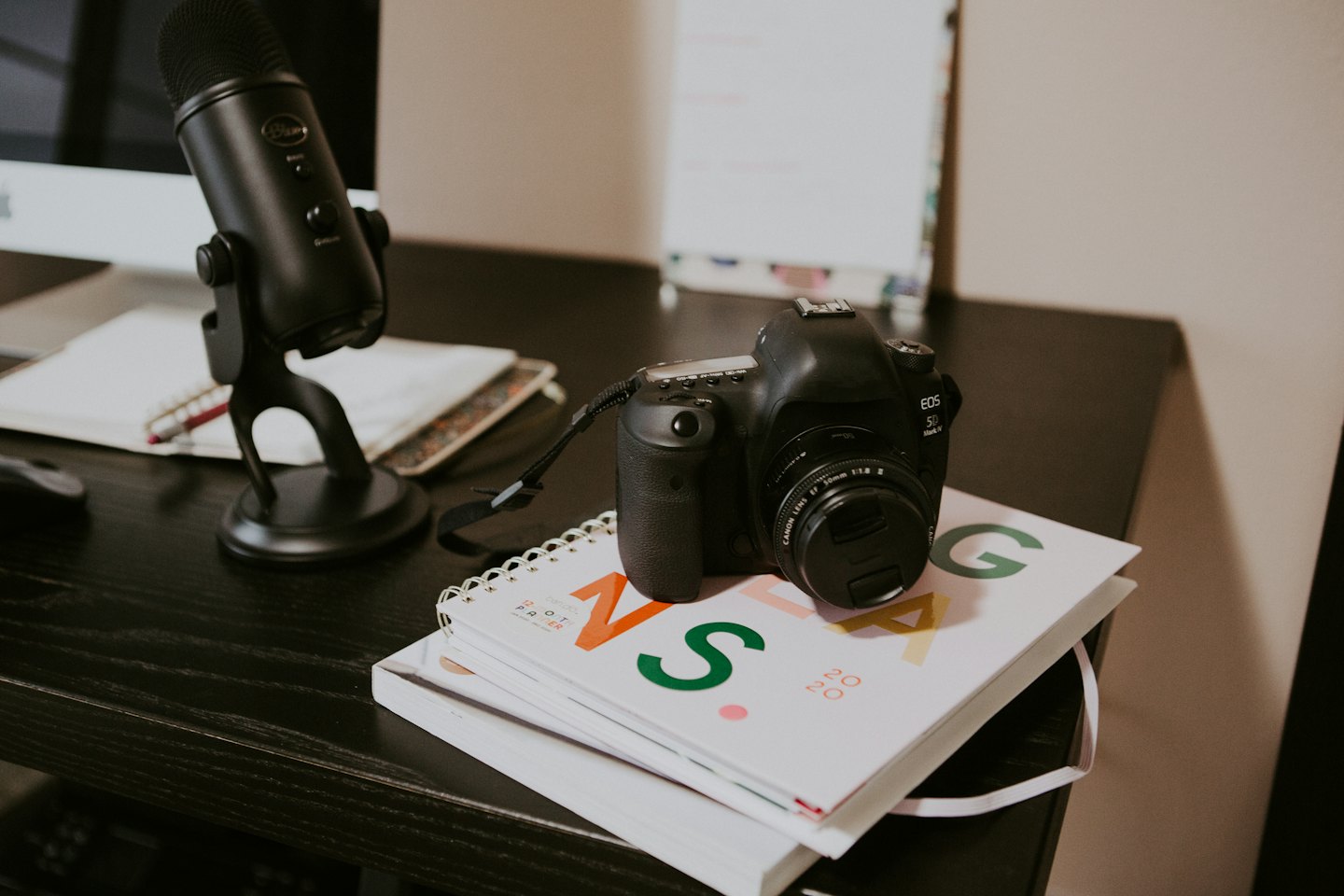Modern creative workspace with microphone, notebook, and camera.