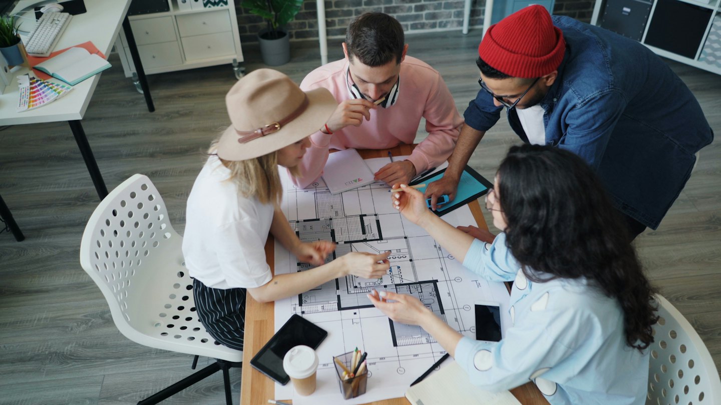 Diverse team collaborates on architectural blueprints in a modern office.